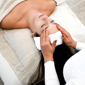 Massaggiatrice professionale esegue un rilassante massaggio linfodrenante del viso.
